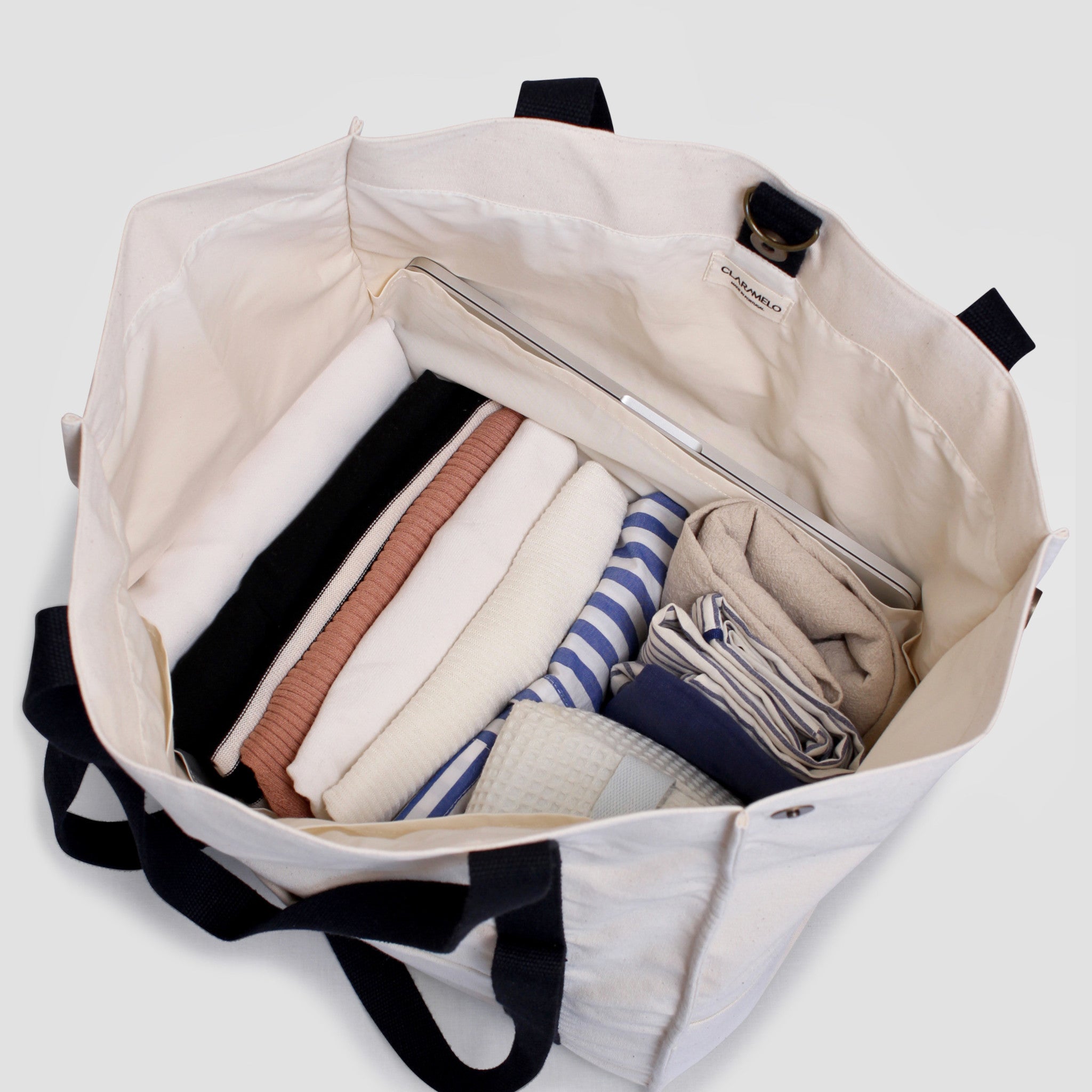 Beige canvas travel bag with black straps, expandable height, exterior zip pocket, trolley sleeve, and interior laptop compartment. Mama Bag and perfect to use as baby bag