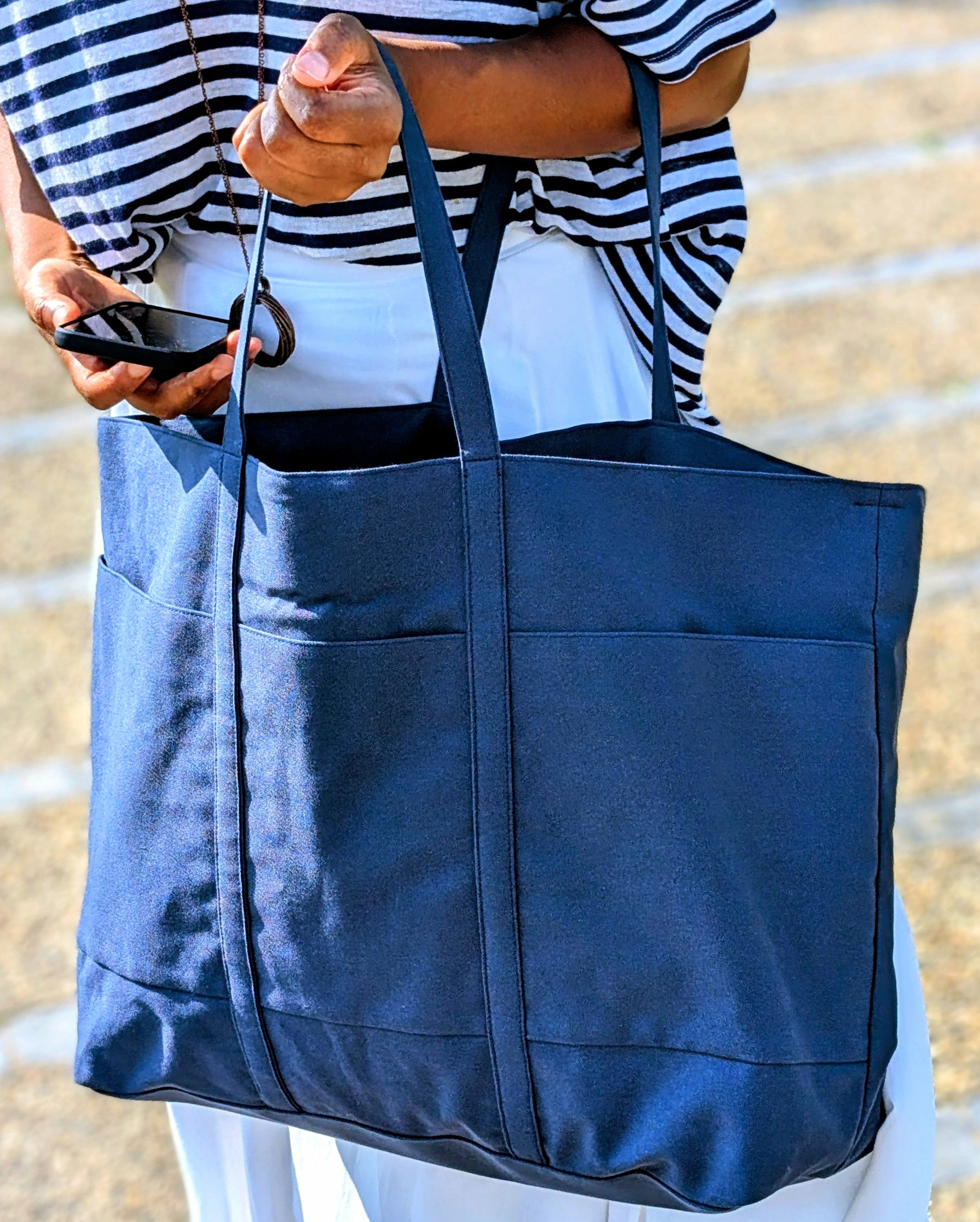 Person holding a blue totebag  on the beach