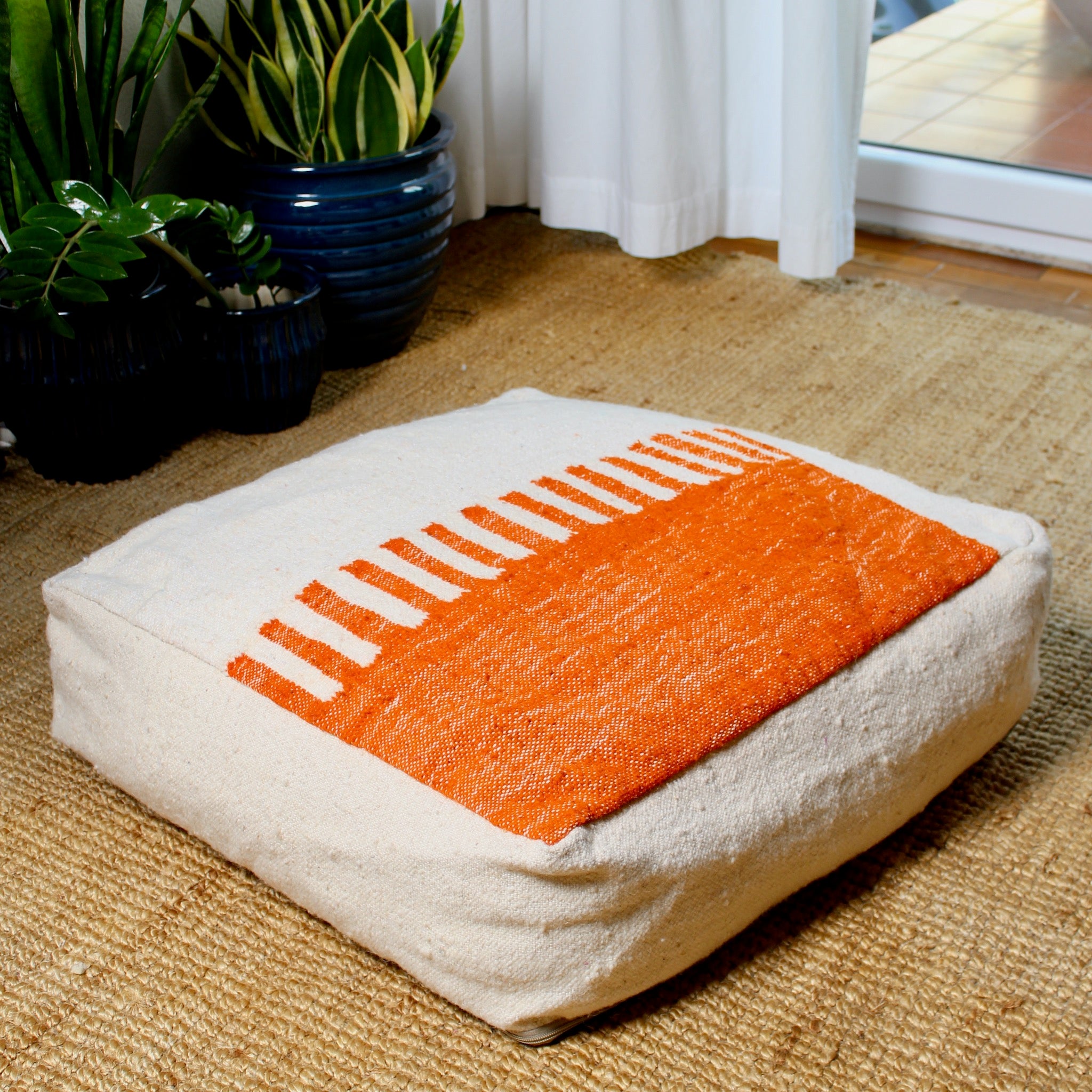 Half beige and half orange Moroccan wool pouf with geometric Berber pattern, 60×60×20 cm, handmade and artisan-crafted floor cushion