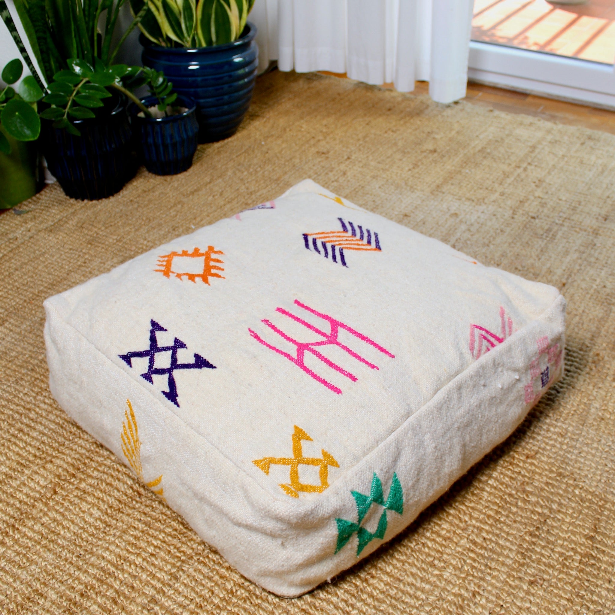 Beige Moroccan wool pouf with multicolor Berber patterns, handcrafted from Azilal rug in the Atlas Mountains, 60×60×20 cm artisan floor pillow