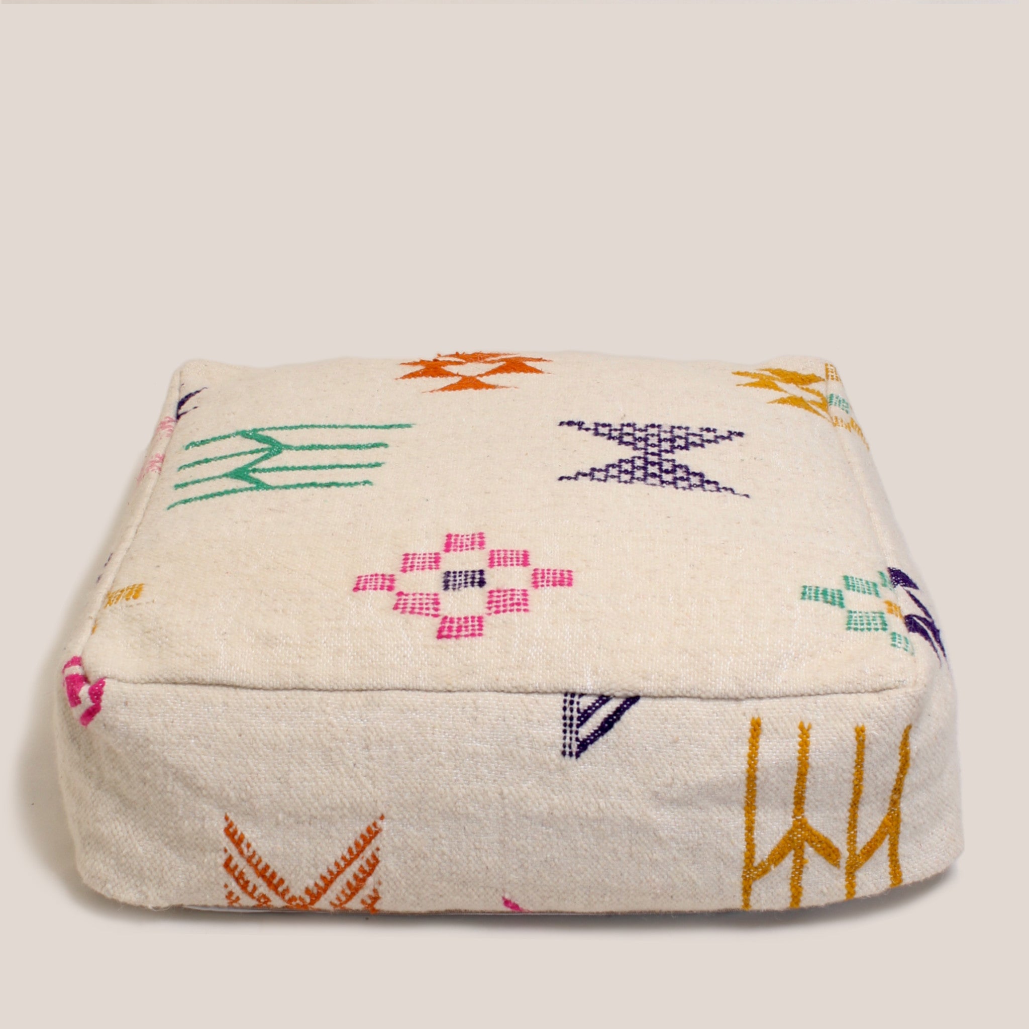 Beige Moroccan wool pouf with multicolor Berber patterns, handcrafted from Azilal rug in the Atlas Mountains, 60×60×20 cm artisan floor pillow